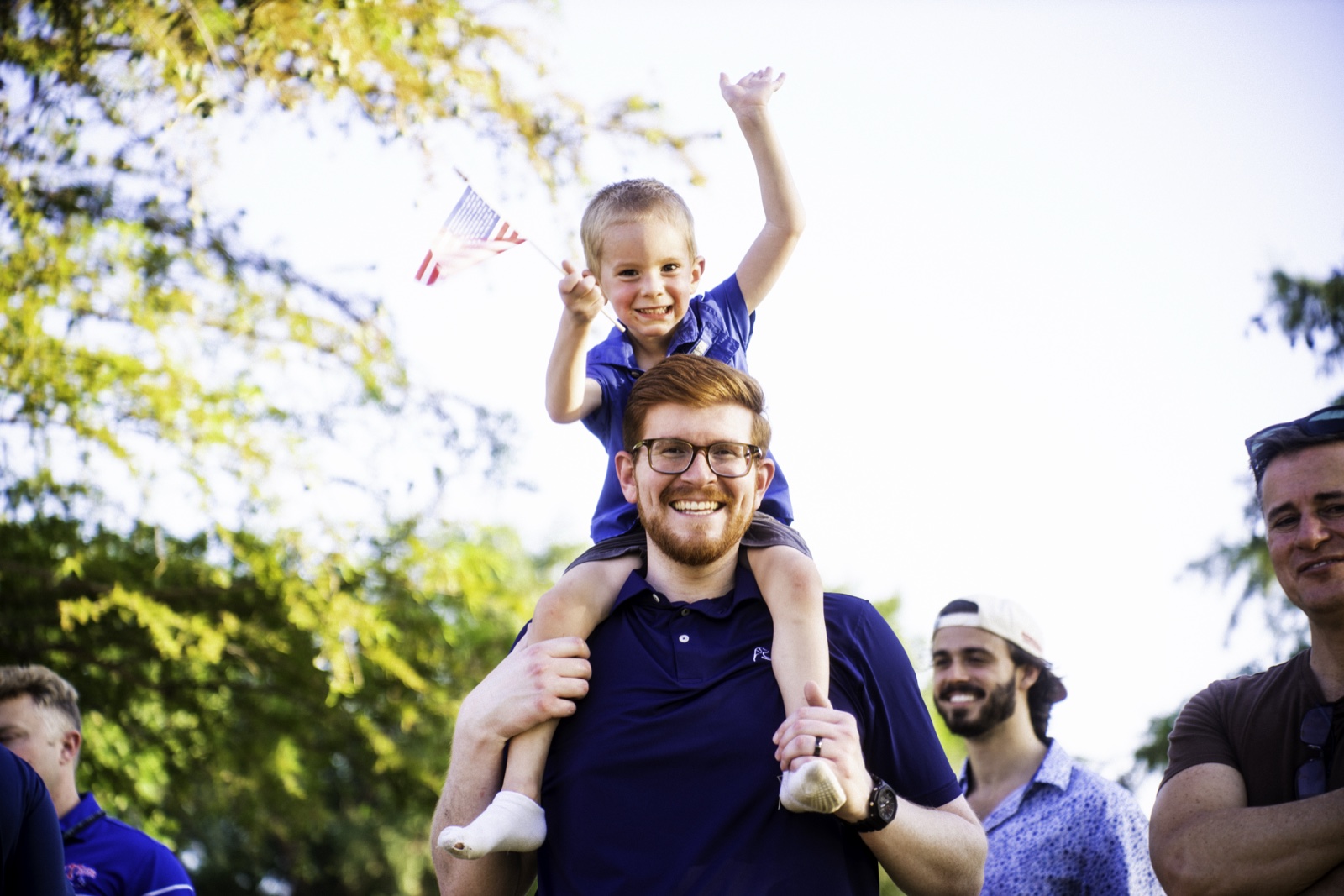 A father and son celebrating with an American flag at the Plano Young Republicans July cookout